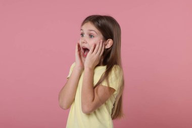 Pembe arka planda şaşırmış bir kızın portresi