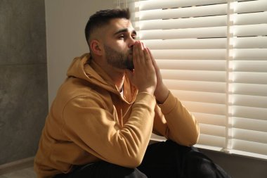 Üzgün genç adam ve pencerenin yanında oturan