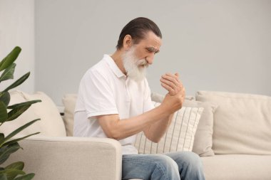 Evdeki kanepede elinde acıdan muzdarip son sınıf öğrencisi. Romatizma belirtileri