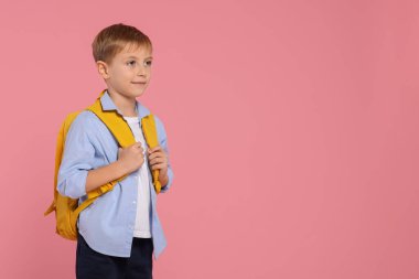 Pembe arka planda sırt çantası olan mutlu okul çocuğu, mesaj için yer var.