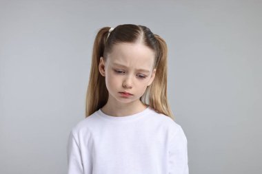 Açık gri arka planda üzgün bir kızın portresi