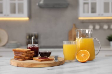Kahvaltı mutfakta servis edilir. Çıtır tost, reçel ve portakal beyaz masada taze.