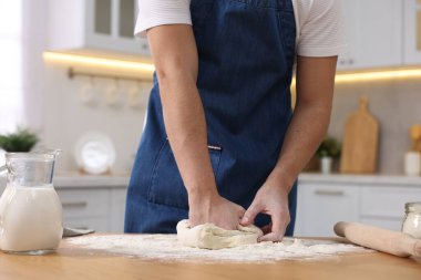 Ekmek yapıyorum. Mutfaktaki ahşap masada hamur yoğuran adam, yakın plan.