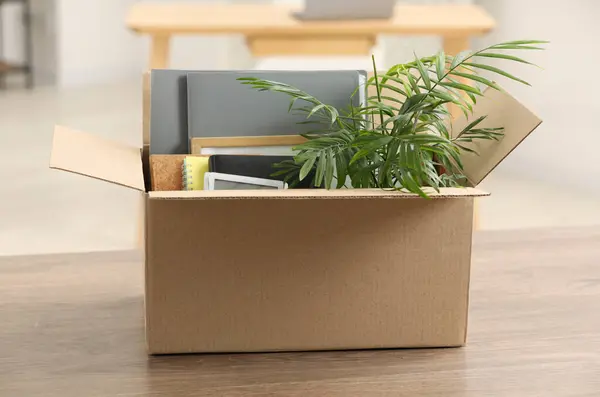 Unemployment problem. Box with worker's personal belongings on table in office
