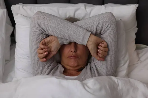Menopause, sleep problems. Woman suffering from insomnia in bed, top view