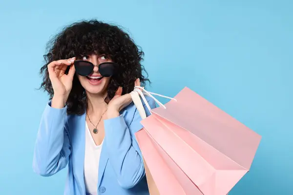 Alışveriş Torbaları Açık Mavi Arka Planda Şık Güneş Gözlükleriyle Mutlu — Stok fotoğraf