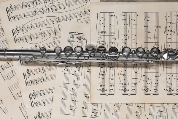 Classical flute on sheets with musical notes, top view