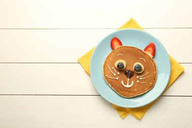 Çocuklar için yaratıcı hizmet. Krep, böğürtlen, krema, muz ve çikolata ezmesinden yapılmış beyaz ahşap masa, üst manzara. Metin için boşluk