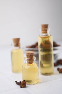 Şişelerdeki karanfil yağı ve beyaz döşemeli masada kurumuş tomurcuklar, yakın plan.