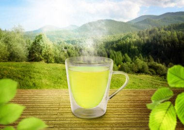 Dağlardaki ahşap masada cam bardakta yeşil çay.