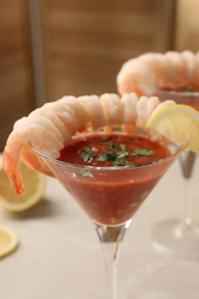Tasty shrimp cocktail with sauce in glasses and lemon on light table, closeup