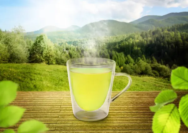 Dağlardaki ahşap masada cam bardakta yeşil çay.