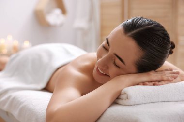 Güzel bir kadın masaj salonundaki masaj koltuğunda dinleniyor, mesaj atmak için yer var.