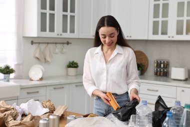 Çöp ayıklama. Mutfakta yemek artıklarını plastik torbaya koyan bir kadın.