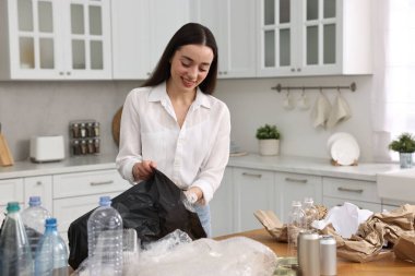 Mutfaktaki çöpleri ayıran gülümseyen kadın.