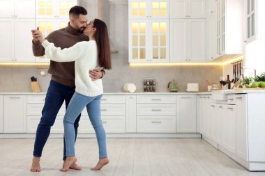 Sevecen genç bir çift mutfakta dans edip öpüşüyor. Metin için boşluk