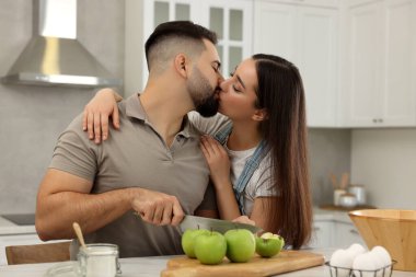Mutlu genç çift mutfakta birlikte vakit geçiriyor.
