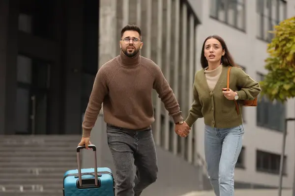 Being late. Worried couple running near building outdoors