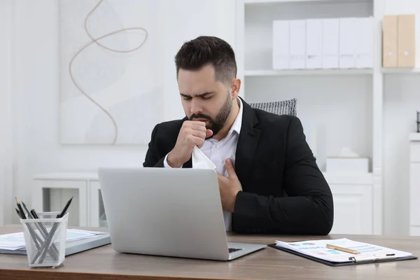 Sick man coughing at workplace in office