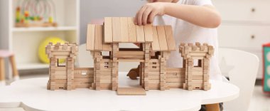 Beyaz masadaki ahşap giriş kapısıyla oynayan küçük çocuk, yakın plan. Çocuk oyuncağı