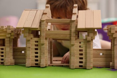 Küçük çocuk odasındaki yapboz paspası üzerinde tahta giriş kapısıyla oynuyor. Seçici bir odak noktası. Çocuk oyuncağı