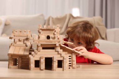 Odadaki tahta kaleyle oynayan şirin küçük çocuk. Çocuk oyuncağı