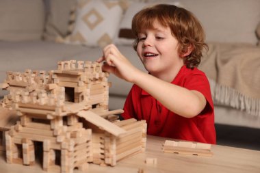 Odadaki tahta kaleyle oynayan şirin küçük çocuk. Çocuk oyuncağı