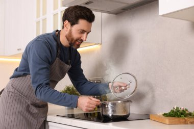 Adam mutfaktaki ocakta çorba pişiriyor.