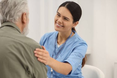 Hastanede yaşlı hastalara bakan gülümseyen hemşire.