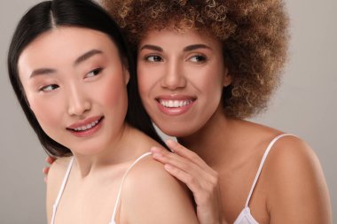 Gri arka planda sağlıklı cilde sahip güzel genç kadınlar.