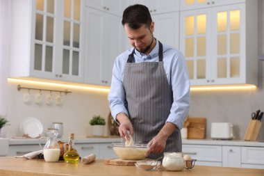 Ekmek yapıyorum. Adam mutfaktaki ahşap masada hamur hazırlıyor.