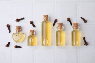 Şişelerdeki karanfil yağı ve beyaz döşeme masasındaki kurumuş tomurcuklar düzdü.