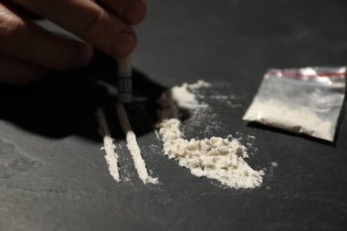 Ağır uyuşturucuya bağımlı bir adam ve bir dolar banknot yuvarlayarak gri dokuma masasında tüketime hazırlanıyor.