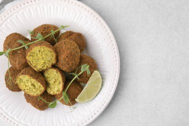 Lezzetli falafel topları, limon dilimi ve ışık masasında mikroyeşiller, üst manzara. Metin için boşluk