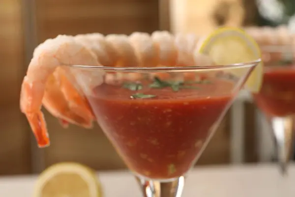 Tasty shrimp cocktail with sauce in glass on blurred background, closeup
