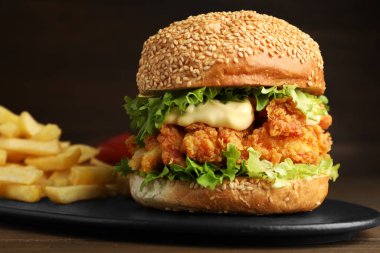 Çıtır tavuk köfteli lezzetli burger ve ahşap masada patates kızartması, yakın plan.