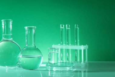 Laboratuvar analizi. Masada yeşil arkaplana karşı farklı cam eşyalar