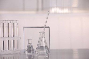 Laboratuvar analizi. Beyaz masa üzerinde sıvı bulunan farklı cam eşyalar, metin için boşluk.
