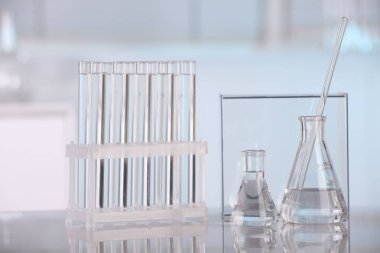 Laboratuvar analizi. Cam mataralar, test tüpleri ve beyaz masada karıştırıcı çubuklar.