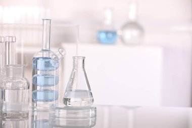 Laboratuvar analizi. Kapalı alandaki beyaz masa üzerinde sıvı bulunan farklı camlar. Metin için boşluk