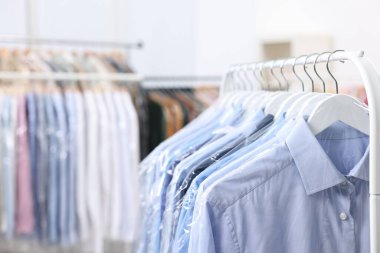 Kuru temizleme servisi. Plastik poşetlerdeki birçok farklı giysi kapalı yerlerde asılı, yakın plan.