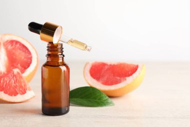 Şişede greyfurt yağı, pipet ve meyveler açık ahşap masada, yakın plan. Metin için boşluk