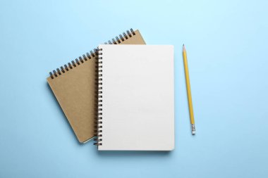 Açık mavi arkaplan üzerinde defterler ve kalem, üst görünüm