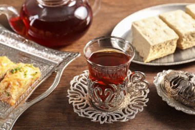 Geleneksel Türk çay ve tatlıları ahşap masada eski çay setinde servis edilir.