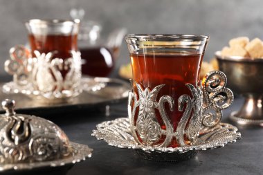 Geleneksel Türk çayı, siyah masa üzerindeki klasik çay setinde servis edilir.