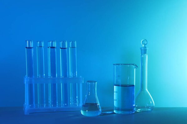 Laboratory analysis. Different glassware on table against blue background