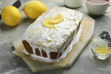 Lezzetli limonlu pasta, turunçgil meyvesi ve gri desenli masa zevki, yakın plan.