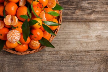 Taze, sulu mandalinalar ve ahşap masa üzerindeki yeşil yapraklar. Metin için boşluk