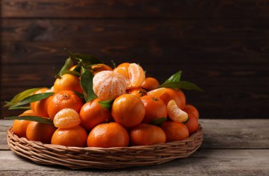 Taze, sulu mandalinalar ve ahşap masada yeşil yapraklar, metin için yer.