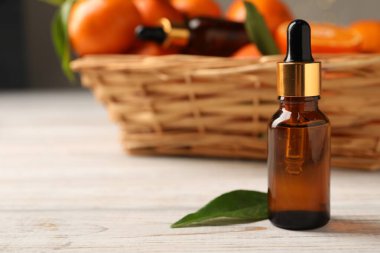 Bir şişe mandalina yağı ve beyaz ahşap masada yeşil yaprak, yakın plan. Metin için boşluk